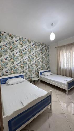 a bedroom with two beds and a wall with a wallpaper at Appartamento Perla in Vlorë