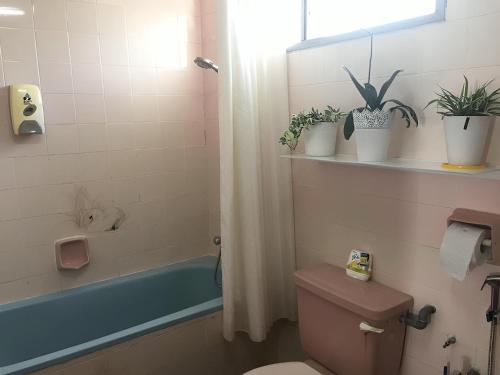 een badkamer met een toilet en een bad met planten bij Bukit Tinggi Fuchsia Hillhomes in Bukit Tinggi