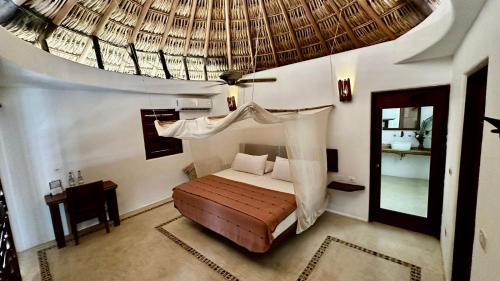 希伯萊特沙灘的住宿－煉金術士瑜伽Spa酒店，一间卧室配有一张带天蓬和镜子的床