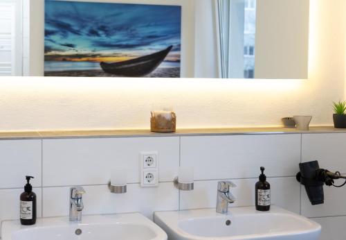 a bathroom with two sinks and a picture of a boat at City Apartment am Zoo & Stadtkern in Leipzig