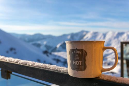 a coffee cup sitting on a balcony overlooking a mountain at Gudauri Mountain Views in Gudauri