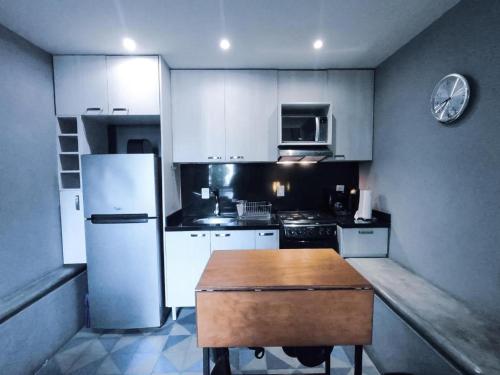 a kitchen with a white refrigerator and a wooden table at La Perla Hotel Boutique B&B in Guadalajara