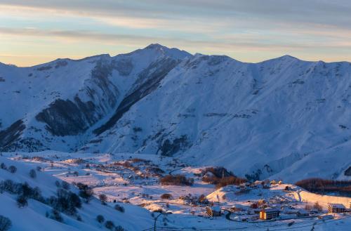 a town in the snow with mountains in the background at Gudauri Mountain Views in Gudauri