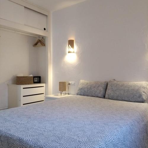 a white bedroom with a bed and a dresser at Es Niuet in Cala Galdana