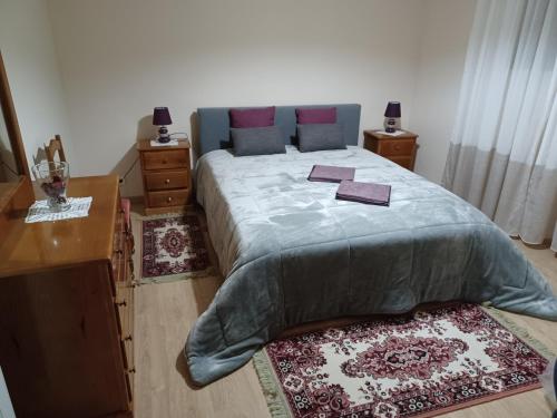 a bedroom with a bed and a desk and two rugs at Casa do Bonifácio in Vilarinho