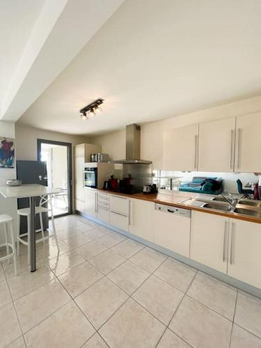 une grande cuisine avec des armoires blanches et une table dans l'établissement Le Romarin - Clim - Vue mer et Jardin - 3 Chbres, à Cassis