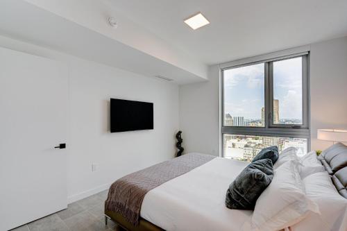 Dormitorio blanco con cama y ventana grande en 227-2903DC DOWNTOWN MIAMI 1 BEDROOM CONDO, en Miami