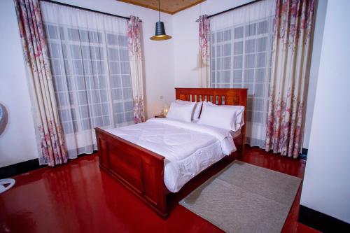 a bedroom with a bed and two large windows at Royal Homestay in Moshi