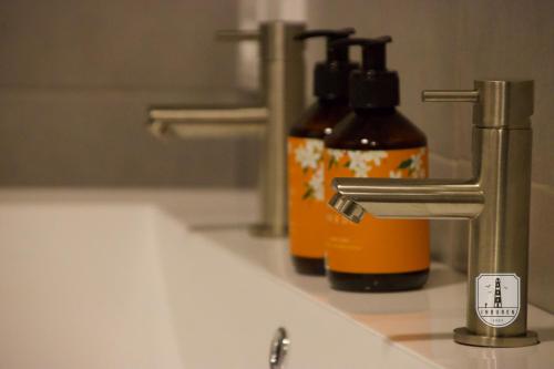 two bottles of soap sitting on a bathroom sink at InBuren in Buren