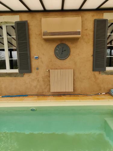 a clock on a wall next to a swimming pool at LE BAS CHITRAY in Ménil