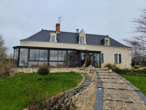 a house with large windows and a stone walkway at LE BAS CHITRAY in Ménil