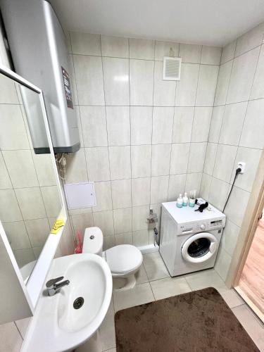 a bathroom with a toilet a sink and a washing machine at Уютная 1 ком квартира Плаза, термопарк in Kostanay