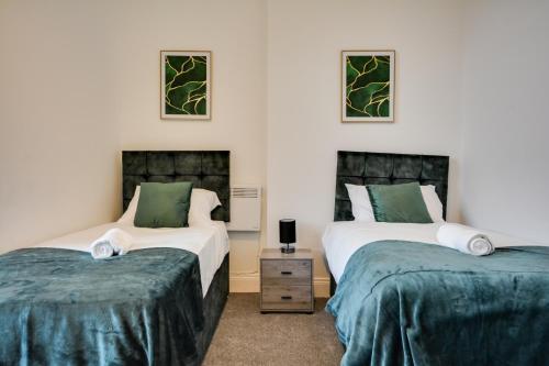 two beds in a room with green and white at Orrell Apartment with free parking in Upholland