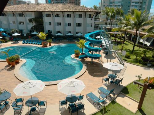 an outdoor swimming pool with chairs and umbrellas at Hotel Aldeia da Praia in Ilhéus