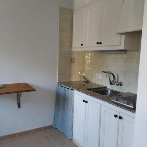 uma cozinha com armários brancos e um lavatório em Es Niuet em Cala Galdana