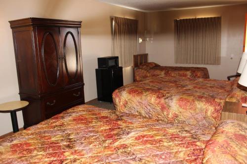 KadokaにあるBudget Host Sundowner Motor Inn Kadokaのベッド2台とドレッサーが備わるホテルルームです。