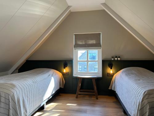 a attic bedroom with two beds and a window at It Gasthûs in Baaiduinen