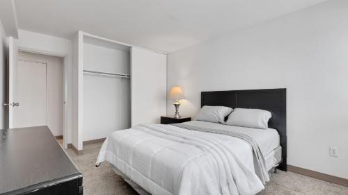 een witte slaapkamer met een groot bed met een zwart hoofdeinde bij Corporate 1br Suite, Pool, Free Parking, Gym Pp in Harrisburg