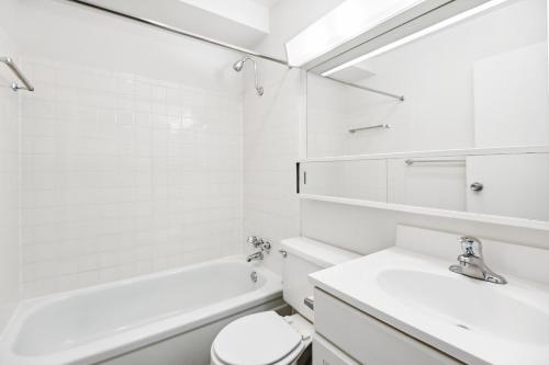 uma casa de banho branca com um lavatório, uma banheira e um WC. em Beautiful Professional 1br Apartment, Pool Pp em Harrisburg