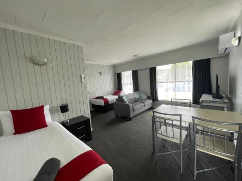 Kensington Motel في وانغاري: غرفه فندقيه بسرير وطاولة واريكه