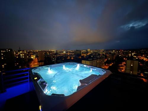 uma banheira de hidromassagem no topo de um edifício à noite em Albelli Luxury Skyview em Košice