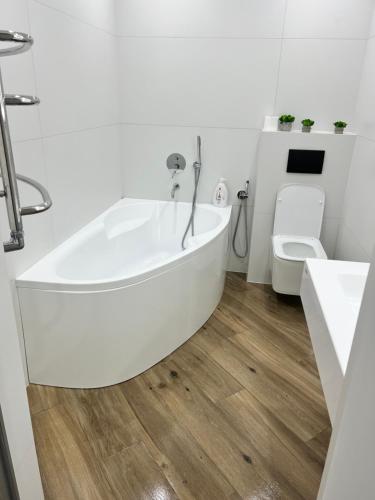 a white bath tub in a bathroom with a toilet at Люкс апартаменты РАЙОН АВТОВОКЗАЛА,в ЖКАрена, ПОБЛИЗУ ОБЛАСНОІ ЛІКАРНІ in Rivne