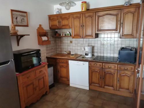 - une cuisine avec des placards en bois et des appareils blancs dans l'établissement La Maison du Vent du Soleil - située au cœur de la Camargue, à Saintes-Maries-de-la-Mer