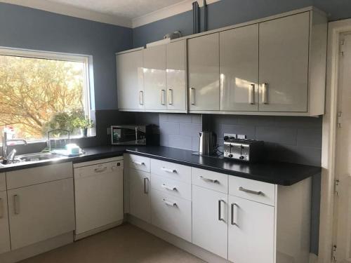 a kitchen with white cabinets and a window at Spacious 5 Large Bedroom Victorian House - Beach 2 Miles in Parkstone