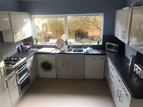 a kitchen with white cabinets and a sink and a window at Spacious 5 Large Bedroom Victorian House - Beach 2 Miles in Parkstone