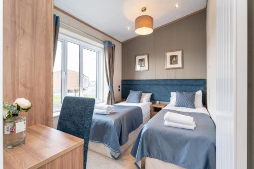a room with two beds and a desk and a window at Stewarts Resort Lodge 18 in St Andrews