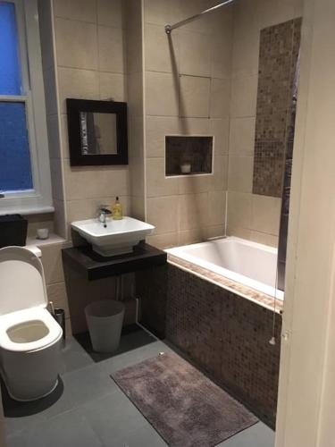a bathroom with a tub and a toilet and a sink at Spacious Flat in West Kensington in London
