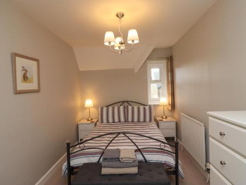 a small bedroom with a bed and two lamps at Jasmine Cottage in Alnwick