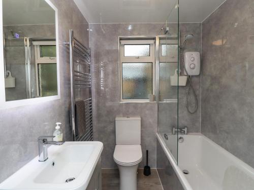a bathroom with a toilet and a tub and a sink at Jasmine Cottage in Alnwick