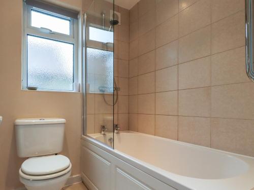 a bathroom with a toilet and a tub and a window at Rose Cottage in Alnwick