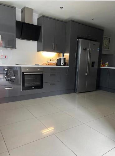a kitchen with gray cabinets and a stainless steel refrigerator at Mac’s- Double Room shared bathroom in Belfast