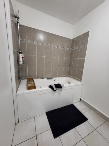 a bath tub with a black rug in a bathroom at Marseille T3 spacieux et paisible avec deux places parking proche vieux port in Marseille