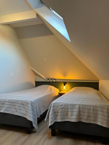 two beds in a attic bedroom with a skylight at It Bûthús in Baaiduinen