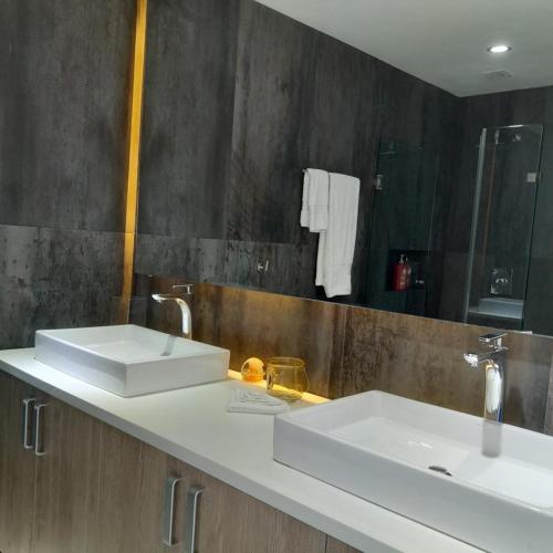 a bathroom with two white sinks and a mirror at Penthouse con Alberca Privada in Playa del Carmen