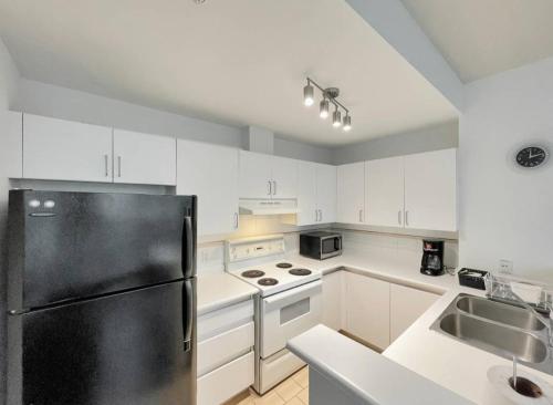 een keuken met witte kasten en een zwarte koelkast bij District West in Vancouver