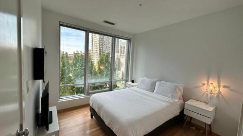 um quarto com uma cama branca e uma grande janela em District West em Vancouver