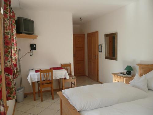 a bedroom with a bed and a table with a television at Landhaus Caesar - Hotel Garni in Bad Heilbrunn