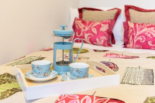 uma bandeja com 2 chávenas e comodidades para preparar café numa cama em The Scarsdale Apartment em Doncaster