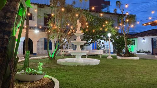 a fountain in the middle of a yard with lights at Pousada Puerta Del Sol Rio das Ostras in Rio das Ostras