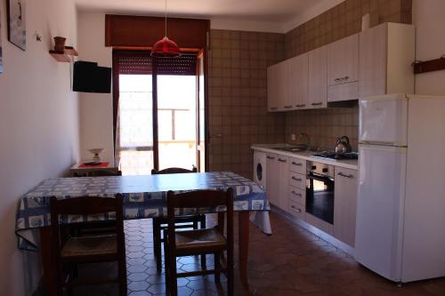アグローポリにあるLa Villetta del Galloのキッチン(テーブル、椅子、冷蔵庫付)