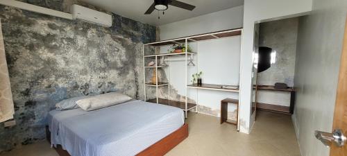 een slaapkamer met een bed en een betonnen muur bij The Stone Elephant - A place to relax in town with Hot Water and a Pool in San Juan del Sur