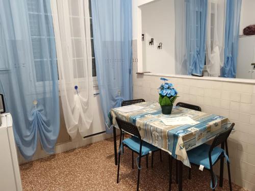 een tafel met stoelen en een tafel met blauwe gordijnen bij Casa di Laura 2 in Genua