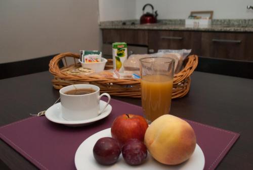 a table with a plate of fruit and a cup of coffee at Links Apart Hotel in Río Grande