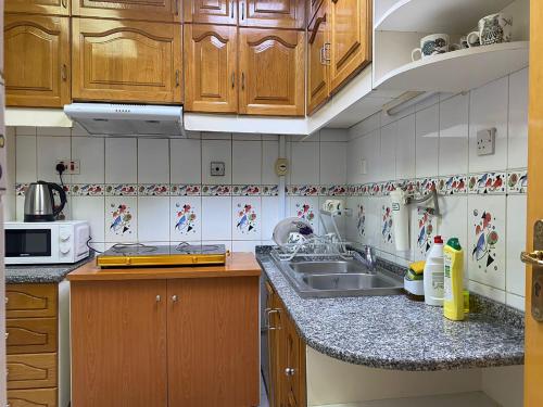 a kitchen with wooden cabinets and a sink at J & F Homestay - Abu Dhabi in Abu Dhabi