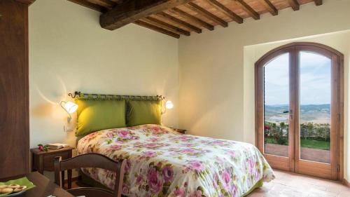 a bedroom with a bed and a large window at Casale con vista colline in Volterra
