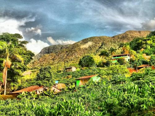 un groupe de maisons sur une colline avec des montagnes dans l'établissement Encanto da Montanha Hospedagem, à Príncipe